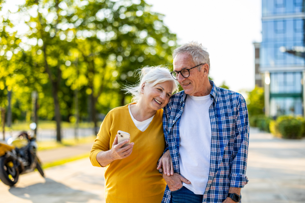 Senior couple in love walking in the city with mobile phone