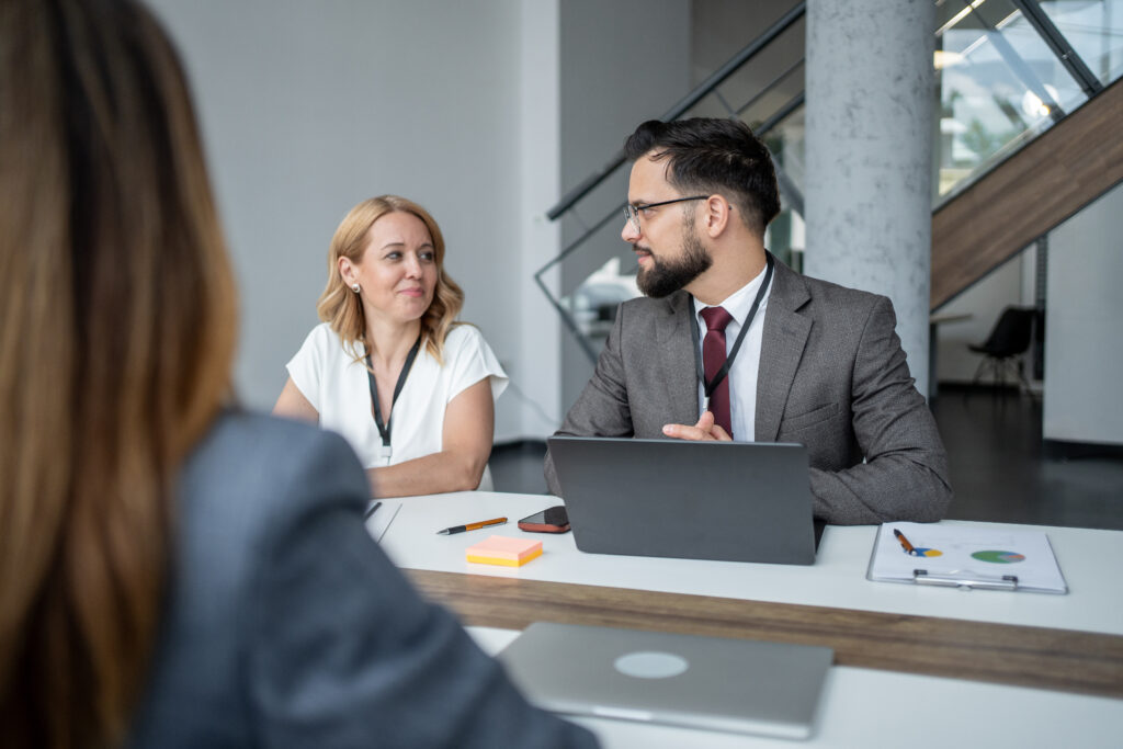 two professionals having a meeting at a table, sitting across from another in the meeting